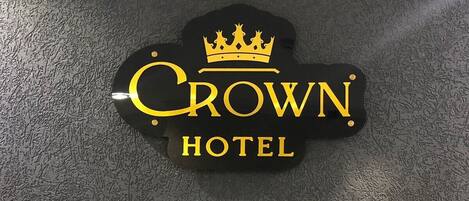 A black sign with the text 'Crown Hotel' and a crown symbol, indicating the hotel's name.