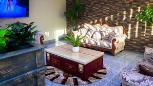 A living room with a sofa, a coffee table, and a TV. - Crown Hotel Piarco (Piarco)