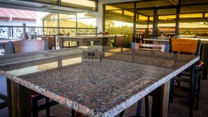 A restaurant with a large granite table, numbered 06, and outdoor seating with a view of the mountains. - Crown Hotel Piarco (Piarco)