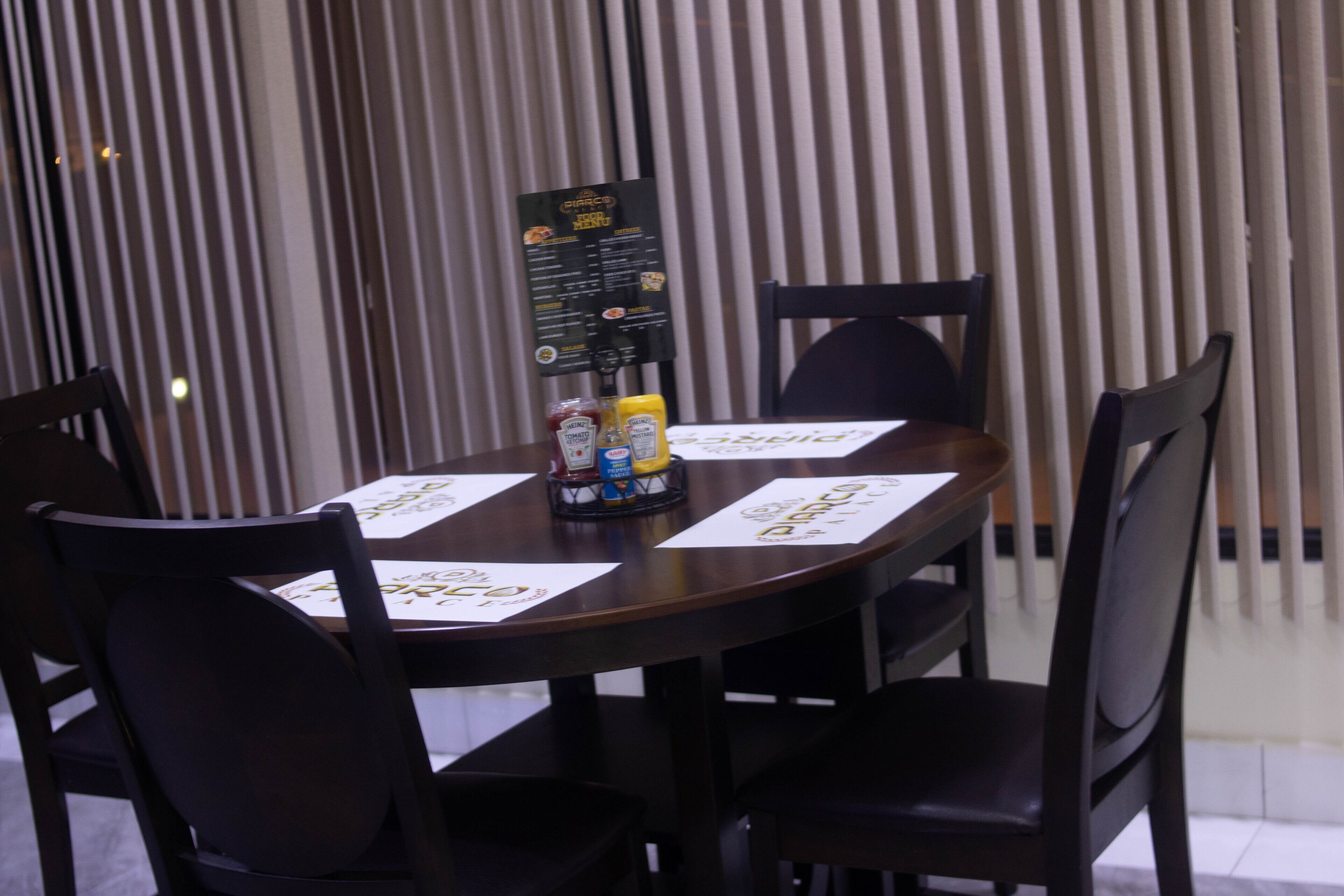 A dining table with four chairs, a menu stand, condiments, and a bottle of water.