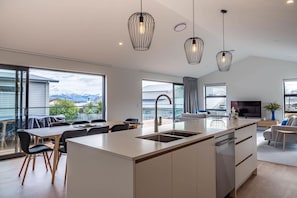 Une cuisine moderne dotée d’un îlot central, de grandes fenêtres et offrant une vue sur les montagnes.