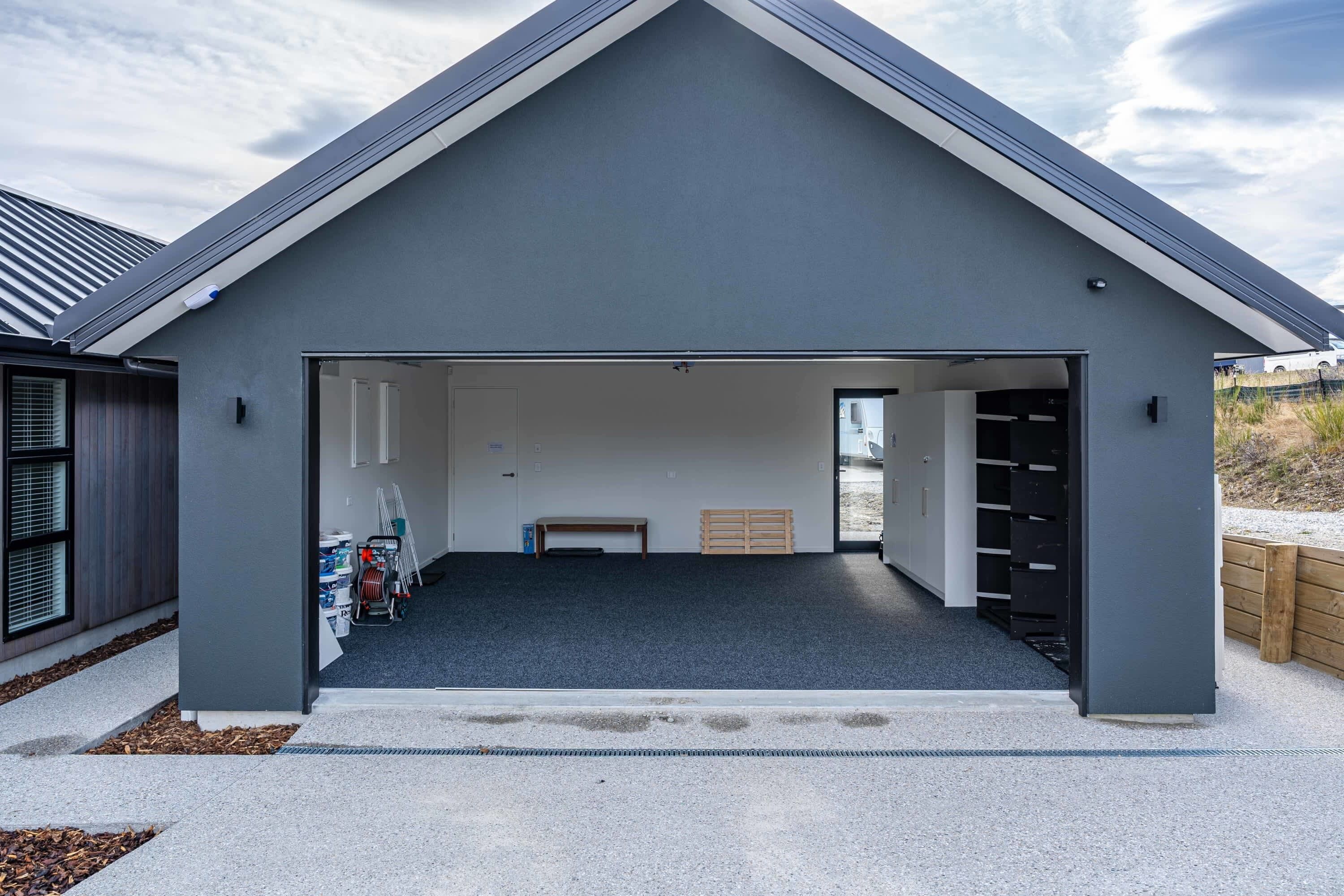 A modern garage with a sloped roof, a concrete floor, and a bench in the center.