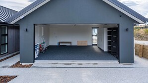 A modern garage with a sloped roof, a concrete floor, and a bench in the center.