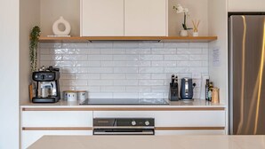 Une cuisine moderne avec des meubles blancs, un réfrigérateur en acier inoxydable et une machine à café.