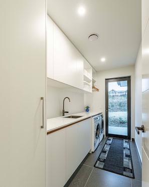 Eine moderne Küche mit Einbauwaschmaschine, Spüle und einer Tür zum Balkon.