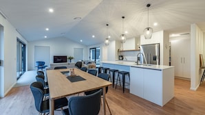 Un espace de vie moderne à aire ouverte comprenant un coin repas, une cuisine et un espace détente.