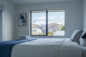 Ein Schlafzimmer mit einem großen Fenster, einem Bett, einem Handtuch und einem gerahmten Bild an der Wand.