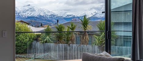 Una sala de estar moderna con un ventanal que da a una cadena montañosa nevada.