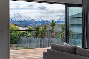 Una sala de estar moderna con un ventanal que da a una cadena montañosa nevada.