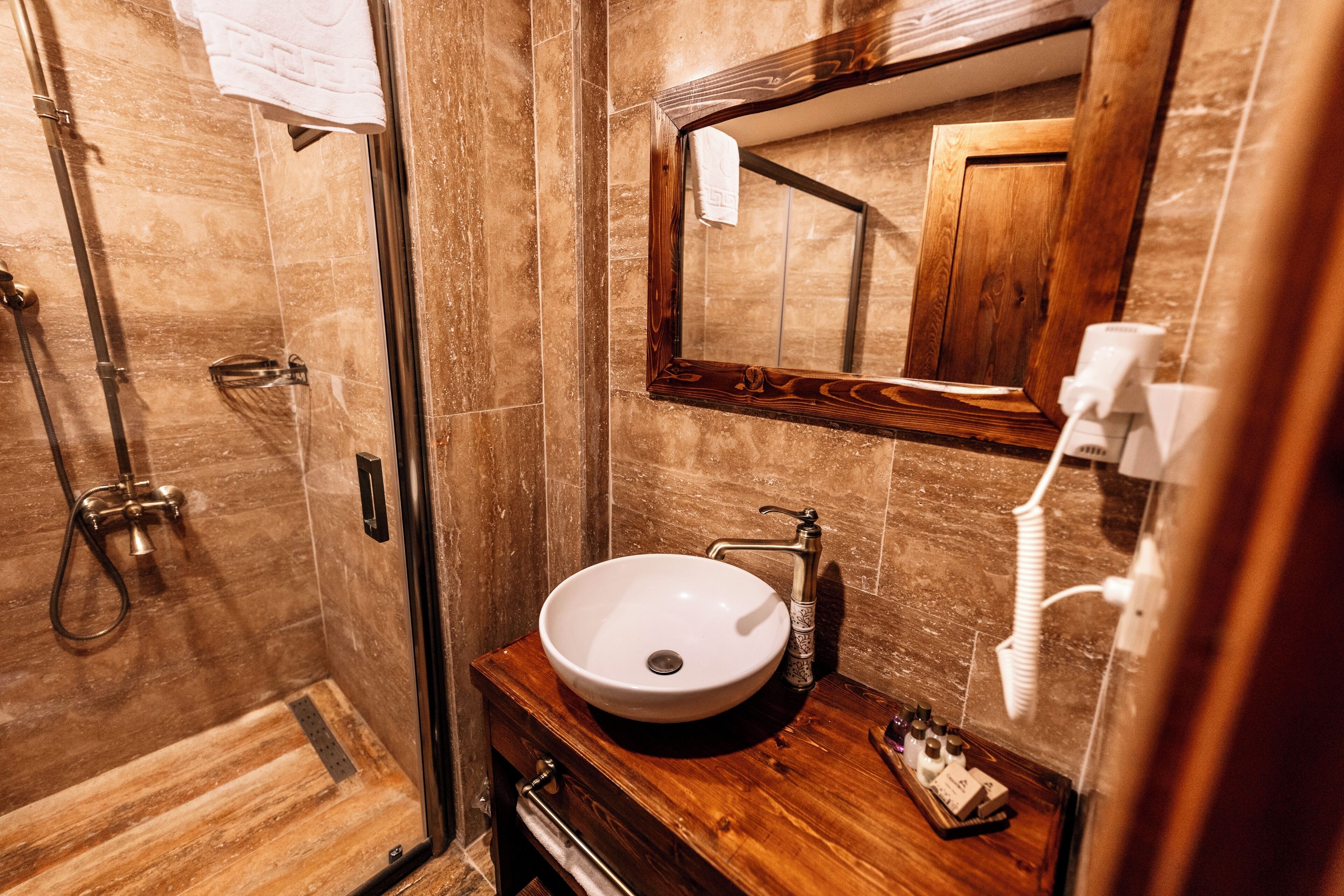Un baño con tocador de madera, un lavamanos blanco y un espejo grande.