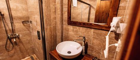 Un baño con tocador de madera, un lavamanos blanco y un espejo grande.