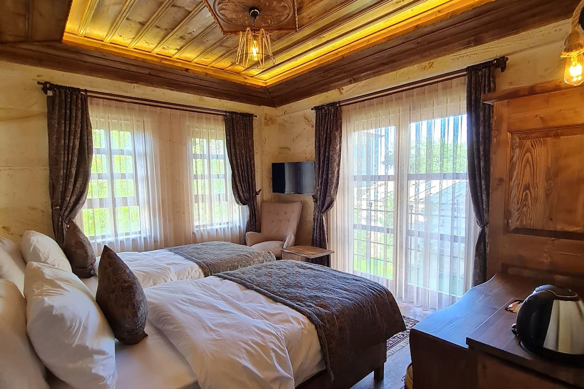 Een slaapkamer met houten lambrisering, een bed, een bureau en een televisie.
