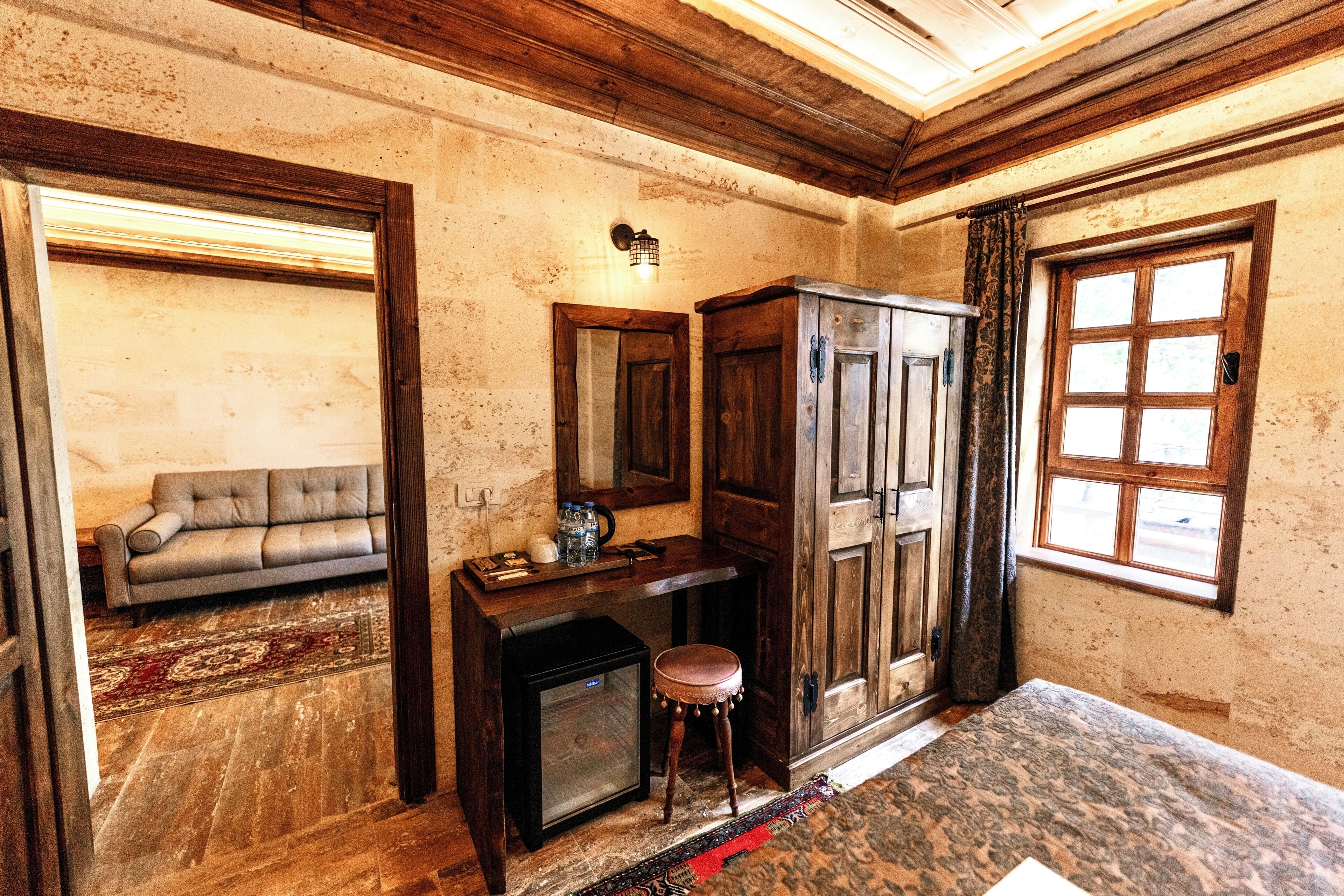 Une pièce comprenant un canapé, un petit tabouret, un bureau avec un miroir et une armoire.