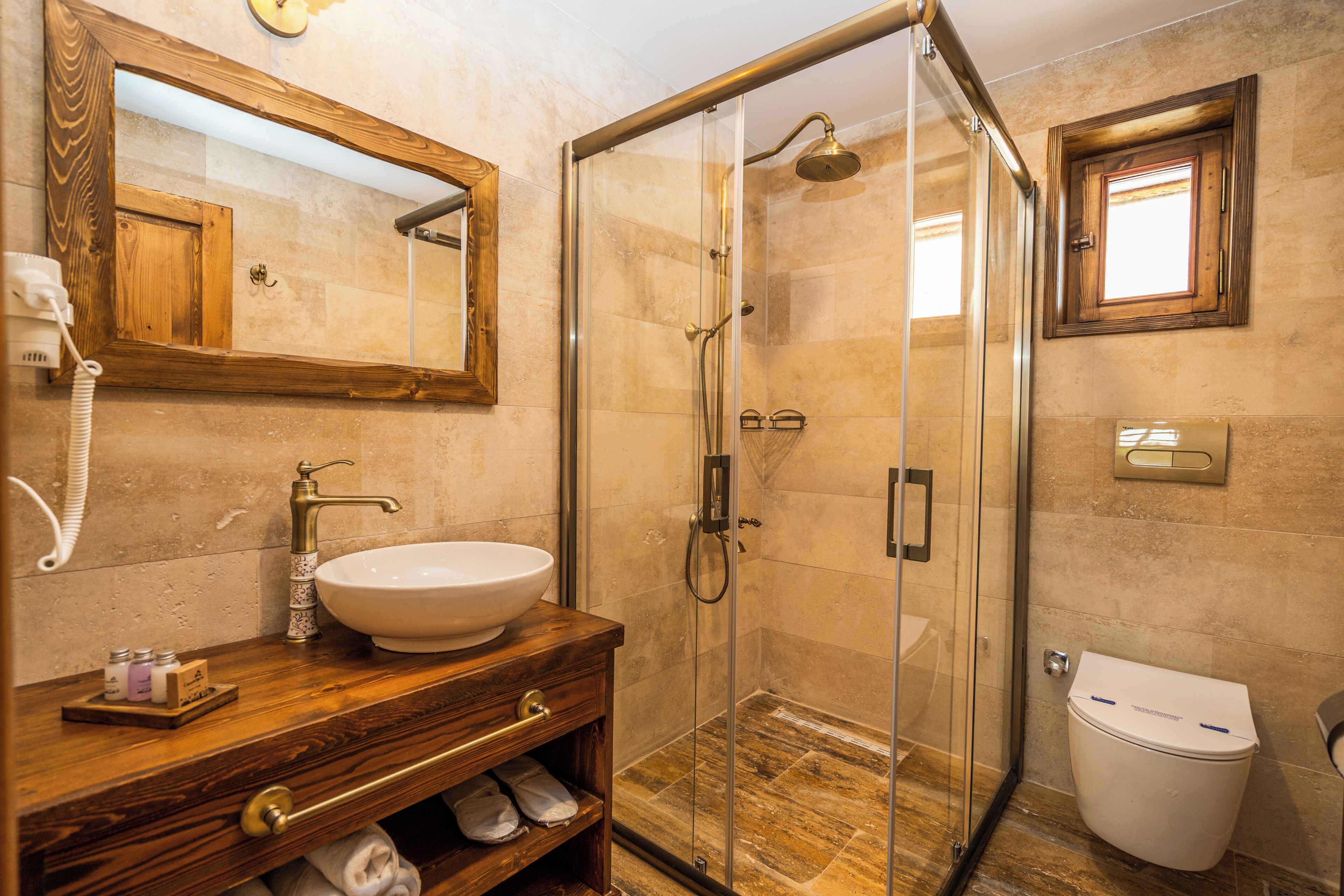 A bathroom with a wooden vanity, a glass-enclosed shower, and a toilet.