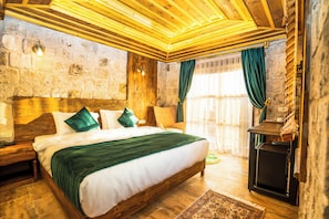 A wooden-framed room with a large bed, stone walls, and a fireplace.