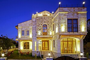 A two-story stone building with a balcony, large windows, and a well-lit entrance. - Flavia Cappadocia Hotel (Nevsehir)