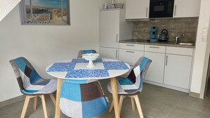 Een moderne keuken met witte kastjes, een magnetron en een koffiezetapparaat.