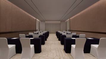 A conference room with rows of tables and chairs, a patterned carpet, and a neutral color scheme.