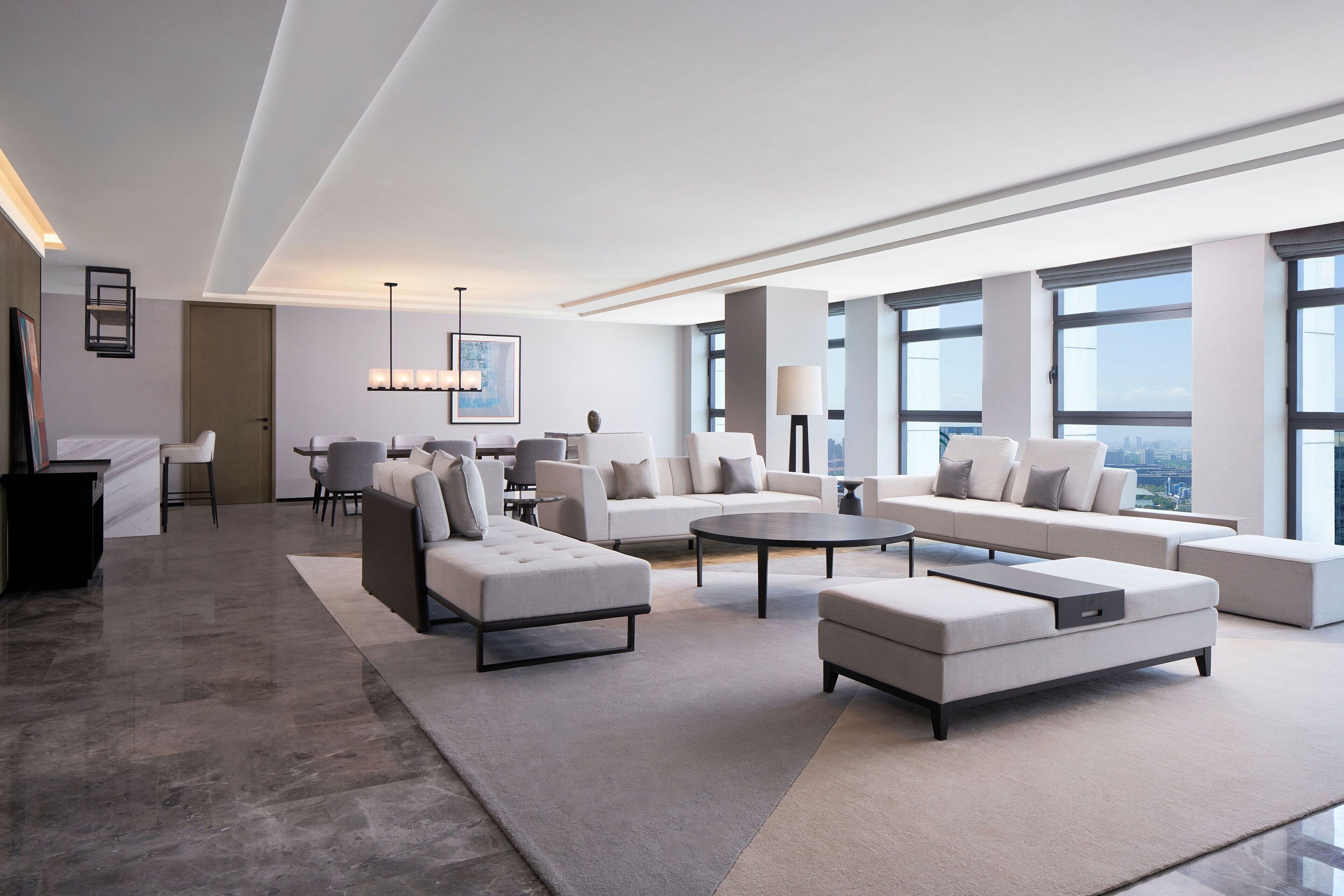 Una sala de estar moderna con un amplio sofá modular, una mesa de centro y un comedor con mesa y sillas.