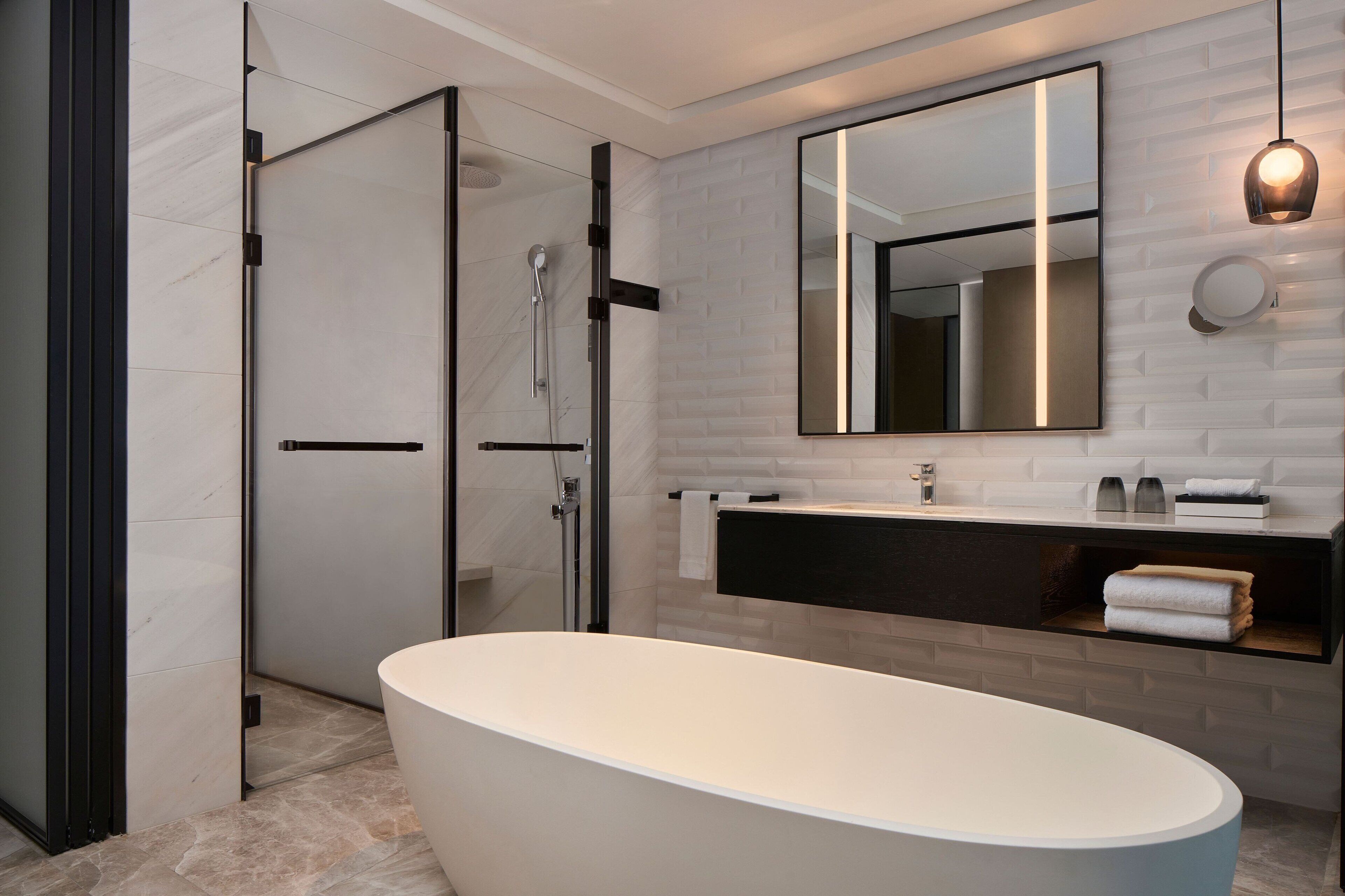 A modern bathroom with a freestanding bathtub, a glass-enclosed shower, and a large mirror above the vanity.