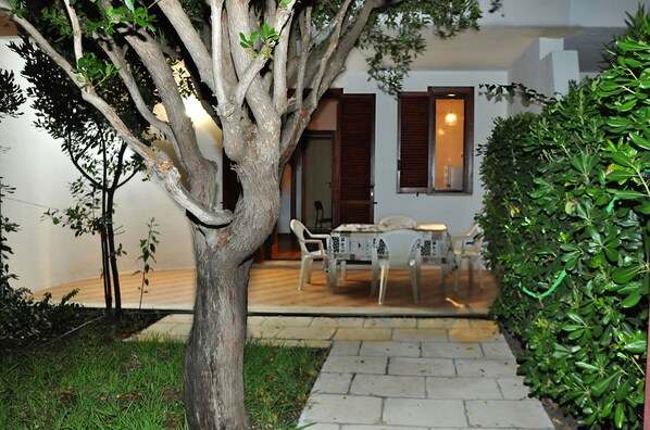 Un sentier bordé d’arbres mène à un espace repas équipé d’une table et de chaises.