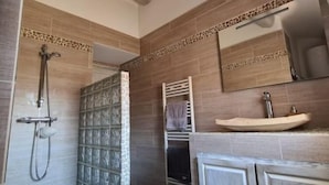 Een badkamer met een douche, wastafel en spiegel.