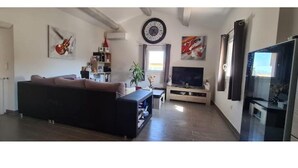 Een woonkamer met een bank, televisie en kunstwerken aan de wanden.