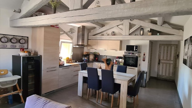 Een keuken met een eetgedeelte, houten balken en een kleine tafel met stoelen.