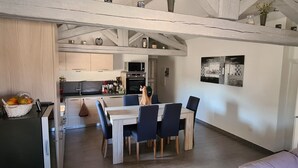 Een compacte keuken met een magnetron, oven en spoelbak. Er is een eethoek met een tafel en stoelen.