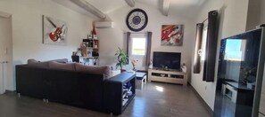 A living room with a sofa, TV, and artwork on the walls.