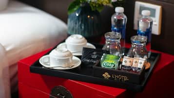 Bandeja de desayuno en una habitación de hotel con bolsitas de té, una botella de agua y un florero.