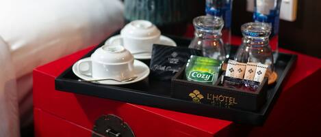 A hotel room's breakfast tray with tea bags, a water bottle, and a vase of flowers.