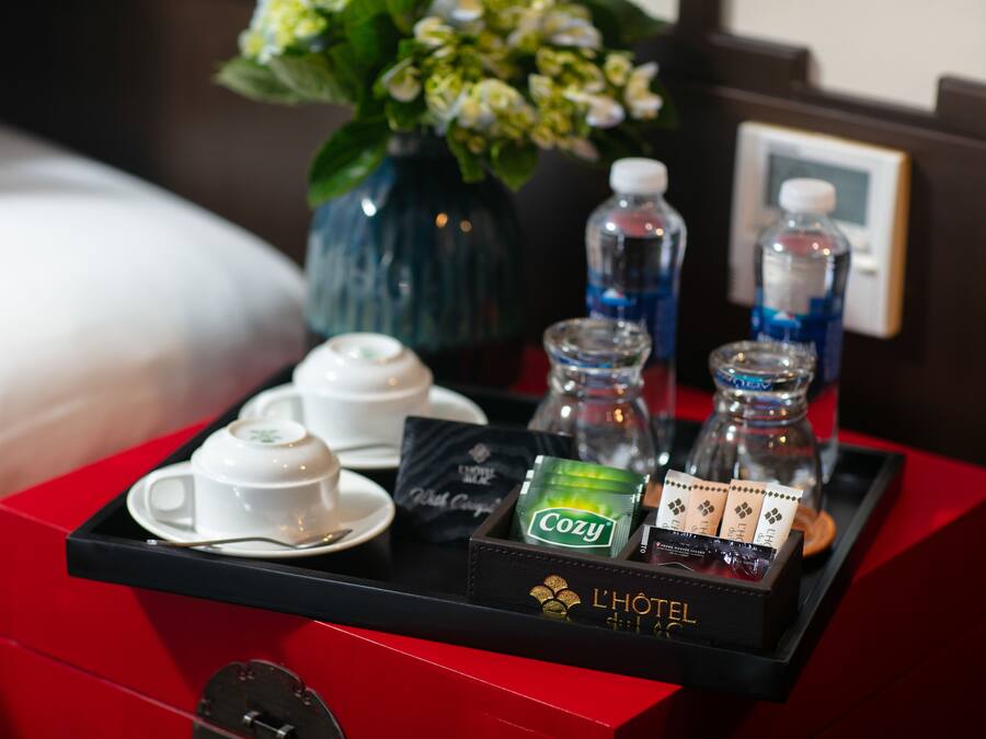 Ein Frühstücksbrettchen im Hotelzimmer mit Teebeuteln, einer Wasserflasche und einer Blumenvase.