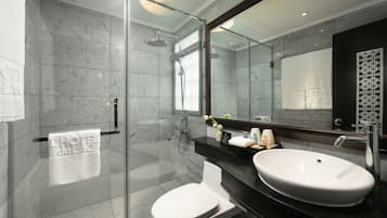 A modern bathroom with a glass-enclosed shower, a white toilet, and a black countertop with a white sink.