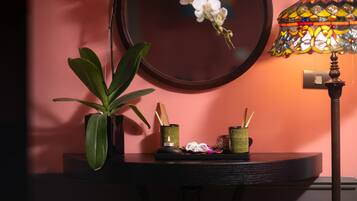 Une table ronde ornée d’un pot de fleurs, d’une lampe décorative et d’un petit plateau sur lequel se trouvent une bougie et des bâtonnets d’encens.