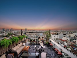 A rooftop terrace with outdoor seating, a city view, and a sunset.