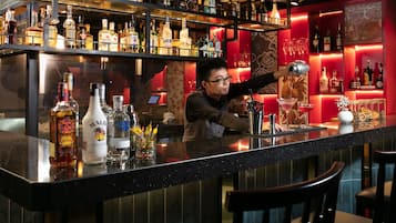 Eine Bar mit Regalen voller Spirituosenflaschen, einem Barkeeper, der einen Cocktail zubereitet, und einer Bar.