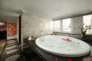 A modern bathroom with a large oval bathtub, a stone pathway leading to the shower, and a city view through large windows.