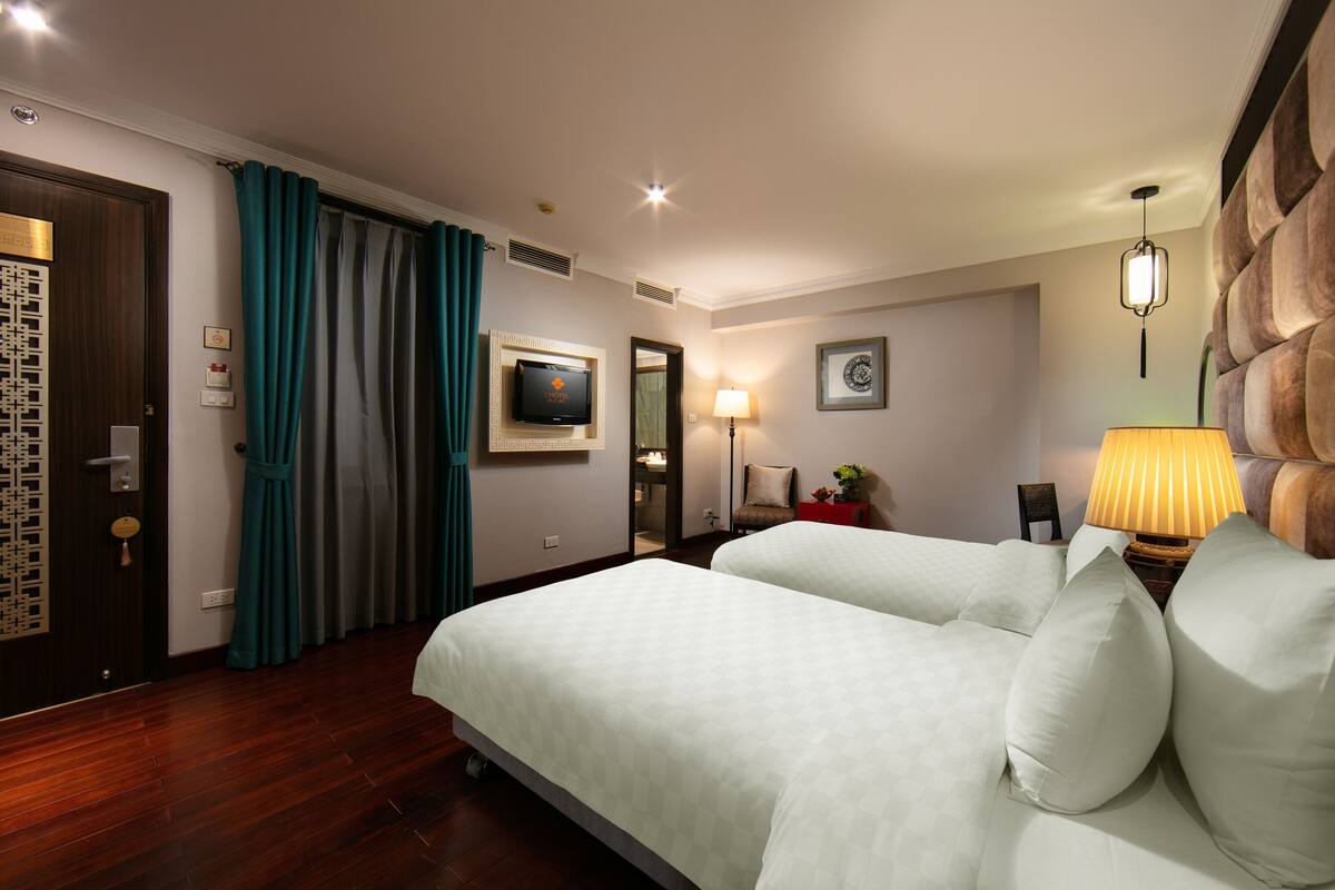 A hotel room with a bed, a TV, a lamp, and a door with a decorative panel.