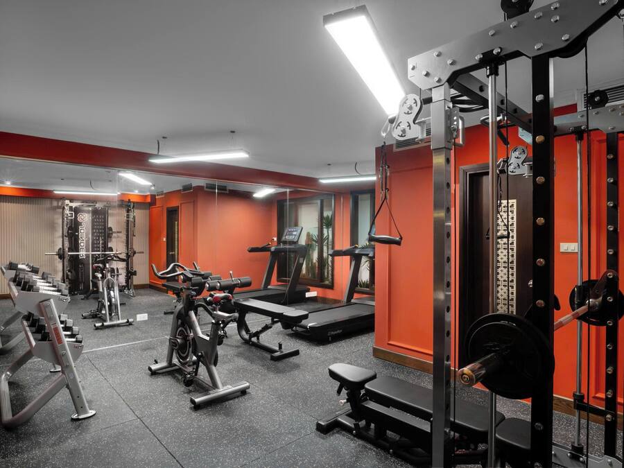 A gym with various exercise equipment, including treadmills and weight machines, and a mirrored wall.