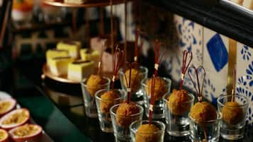 A selection of food items, including small cups with golden-brown balls and skewers, and a variety of other dishes on a table.
