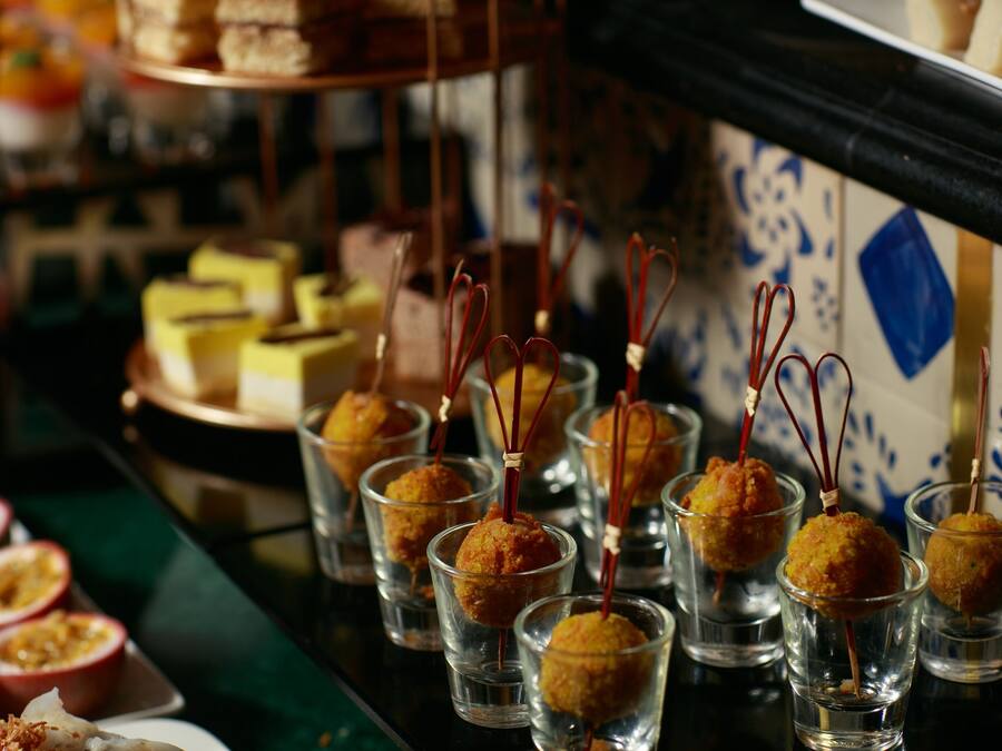 A selection of food items, including small cups with golden-brown balls and skewers, and a variety of other dishes on a table.