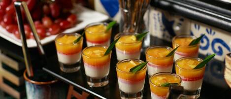 Un buffet de desserts proposant des parfaits aux fruits en couches, ainsi qu’un assortiment de fruits frais et de couverts.