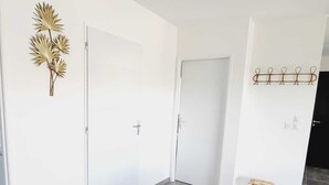Ein Zimmer mit grauen Fliesenböden, weißen Wänden und einer hölzernen Bank.