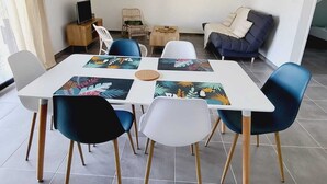 Ein moderner Essbereich mit einem weißen Tisch, blau-weißen Stühlen und einer hängenden Leuchte.