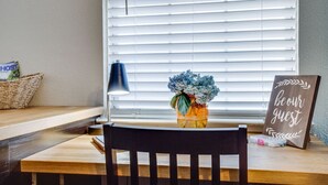 A wooden chair, a lamp, a vase with flowers, a sign saying 'be our guest,' and a basket on a table by a window with blinds. - prof cleaned*Peaceful & Close 2 Dwntwn (Dallas)
