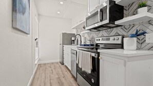 A modern kitchen with white cabinetry, a microwave, an oven, and a coffee maker. - Month Discount!Quiet Studio Apartment*Walk to UTA* (Arlington)