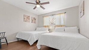 A bedroom with two beds, a ceiling fan, and artwork on the walls. - Walk to AT&T! Family-Friendly 2 Queen Beds (Arlington)