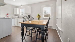 A modern kitchen with white cabinets, a wooden dining table, and black chairs. - Walk to AT&T! Family-Friendly 2 Queen Beds (Arlington)