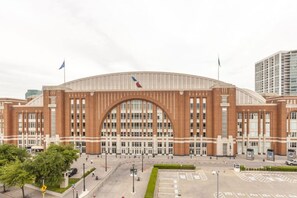 A large, modern building with a prominent arched entrance, multiple flagpoles, and a parking lot. - Bishop Arts 1BR Cozy & Walkable - Month Discount! (Dallas)